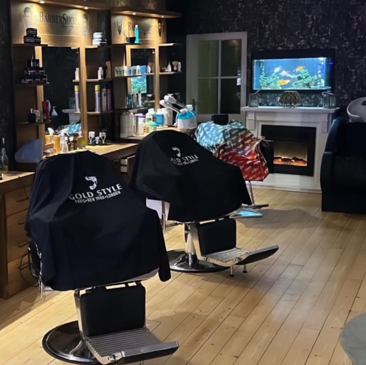 Stoelen met zwarte Gold Style-mantels en een aquarium in de kapsalon