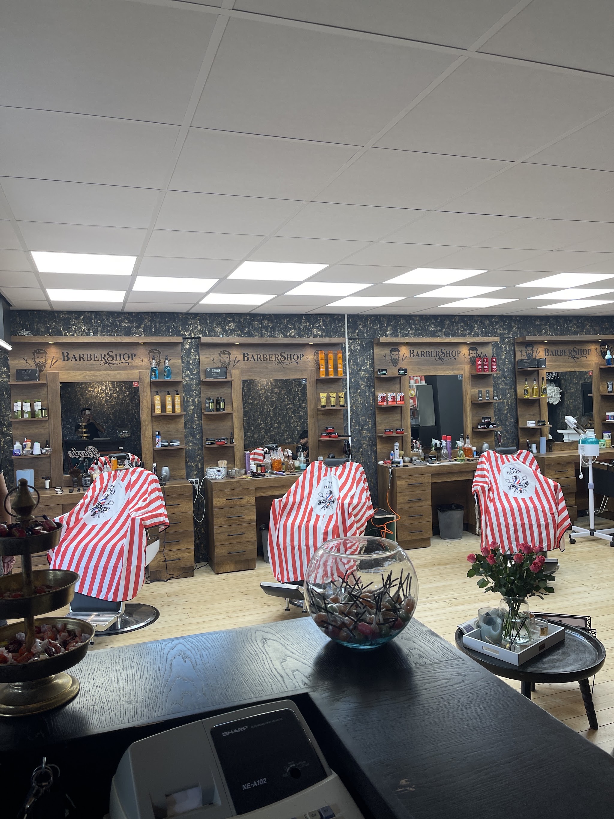 Interieur van Kapsalon Gold Style: drie stoelen met gestreepte kapmantels onder houten Barber Shop-spiegels