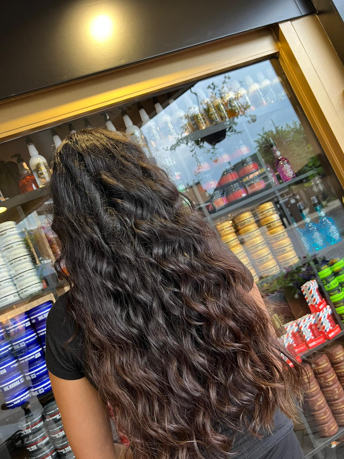Lang, golvend donker haar van achteren gezien voor de productkast van Kapsalon Gold Style
