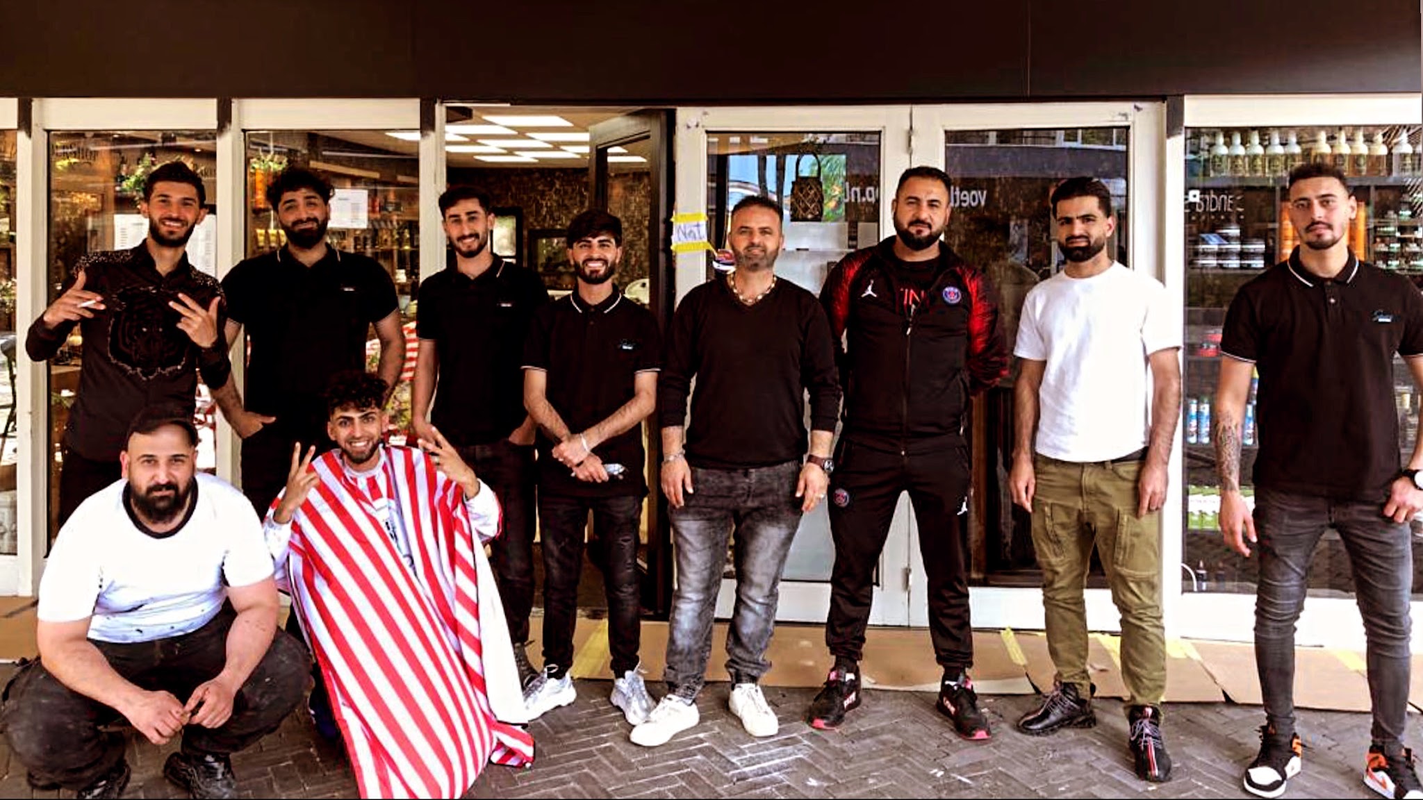 Het team van Kapsalon Gold Style, negen mensen, voor de zaak aan de Noorderstraat in Emmen