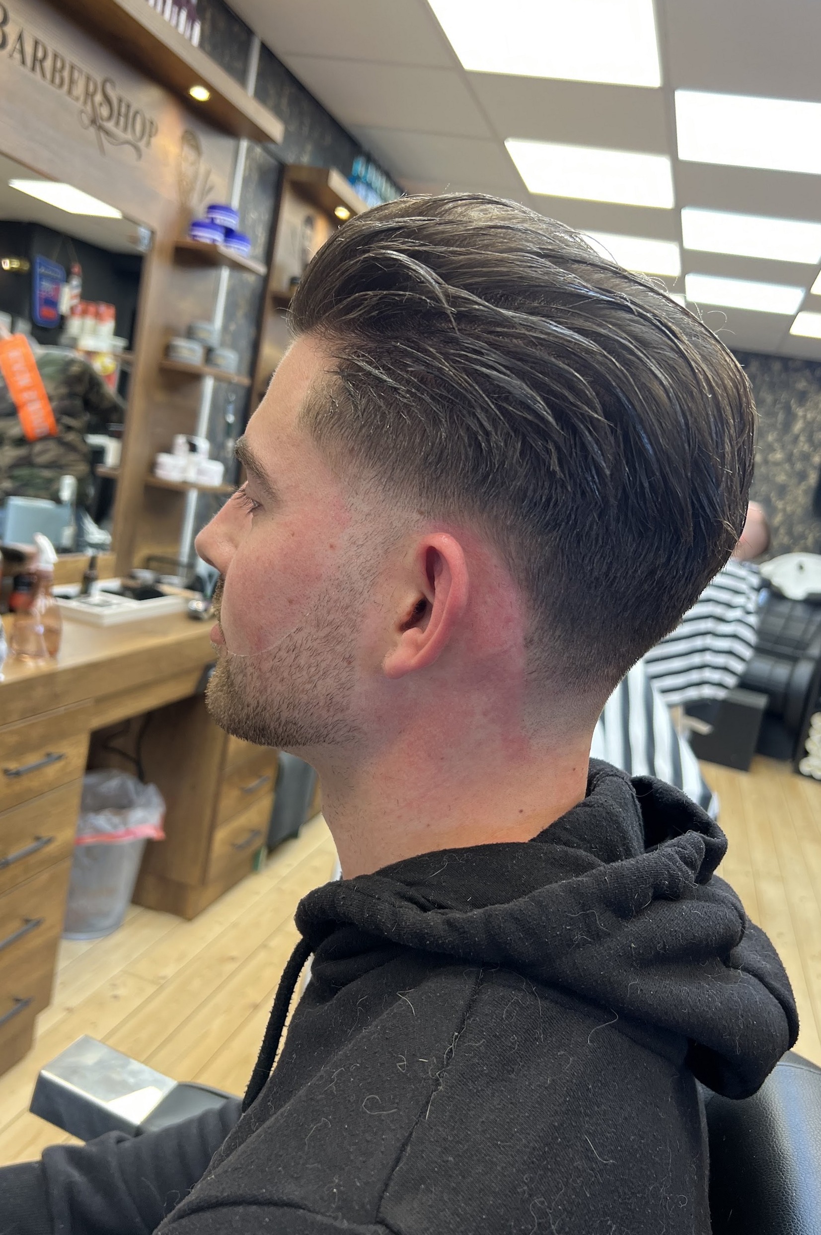 Zijaanzicht van een strakke skin fade met kuif, gemaakt bij Kapsalon Gold Style